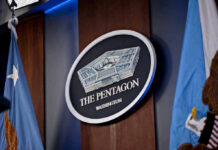 Trump Greenlights Firing Squad The Pentagon emblem between two flags.