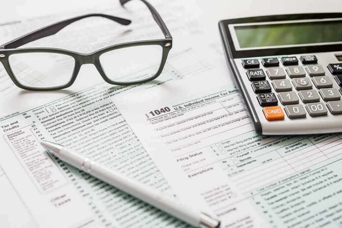 shutterstock_1011737299 Tax forms with calculator, glasses, and pen