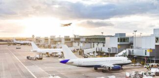 Airplanes at airport gates during sunset with ground vehicles and jet bridges