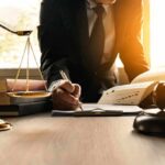 Justice System Misfires – Twice Lawyer writing at desk with scales and gavel