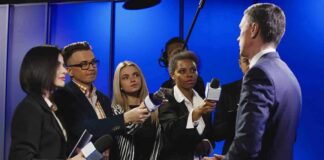 Journalists interview a man in a suit with microphones