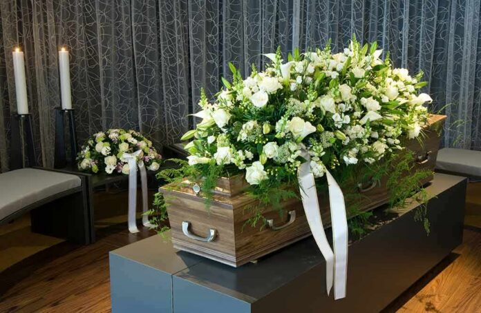 shutterstock_104493380 Coffin with white flower spray in a funeral setting