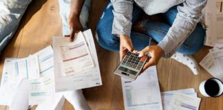 People sitting on floor calculating bills with a calculator