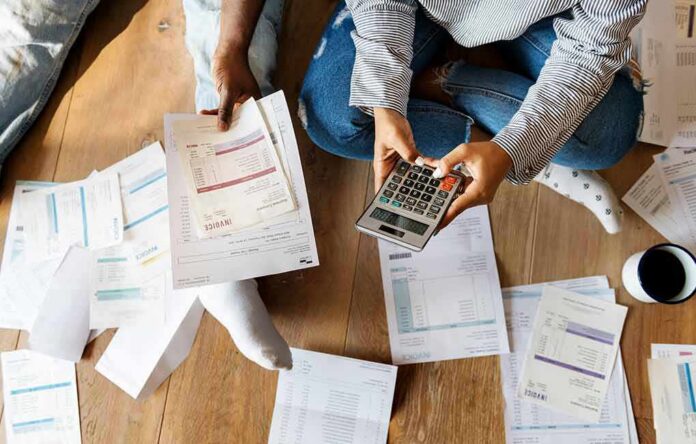 People sitting on floor calculating bills with a calculator