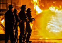 Wind-Whipped Inferno Slams OC Suburbs Firefighters battling a large blaze with a hose