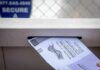 Election System Strain Warning in Michigan Mail-in ballot being inserted into a secure drop box slot