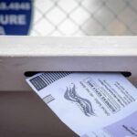 Election System Strain Warning in Michigan Mail-in ballot being inserted into a secure drop box slot
