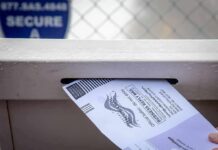 Election System Strain Warning in Michigan Mail-in ballot being inserted into a secure drop box slot