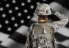 Marine Murder Shock Triggers Japan Fury Soldier in camouflage saluting before a U.S. flag