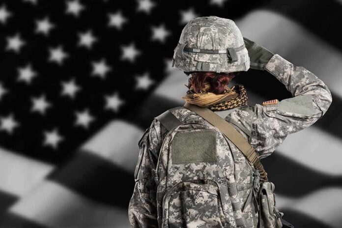 shutterstock_1312887095 Soldier in camouflage saluting before a U.S. flag