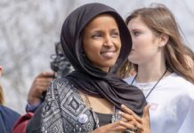 Feds Probe Rep. Ilhan Omar – What’s Hidden? Ilhan Omar wearing a black headscarf at an outdoor event