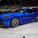 SpaceX Thrusters Flip Tesla Mid-Air Blue sedan on display at an auto show