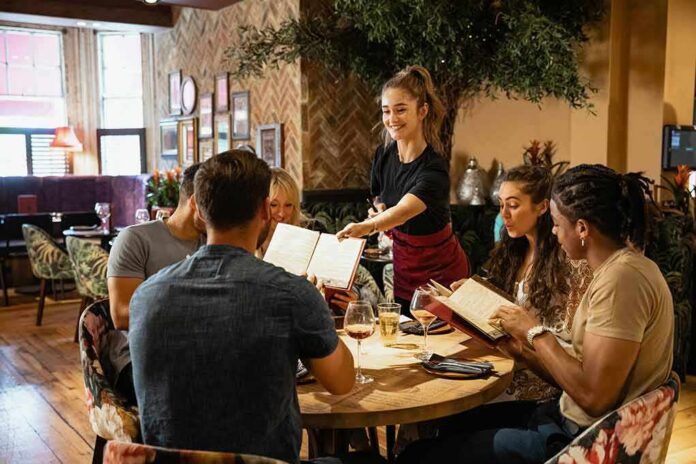 shutterstock_1625111101 Server taking orders from a group at a restaurant table