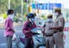 Christian Jones on a scooter speaking with police officers at a roadside checkpoint
