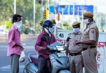 Christian Jones on a scooter speaking with police officers at a roadside checkpoint