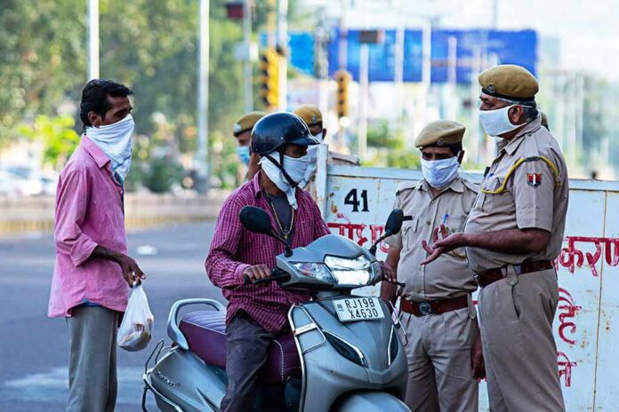 Christian Jones on a scooter speaking with police officers at a roadside checkpoint