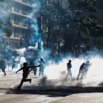 Tear Gas Hits Paris Students Protesters running through tear gas on a city street