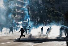 Tear Gas Hits Paris Students Protesters running through tear gas on a city street