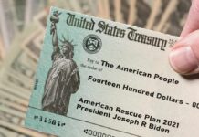 United States Treasury check held over a stack of cash