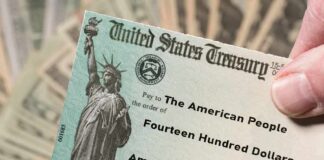 United States Treasury check held over a stack of cash