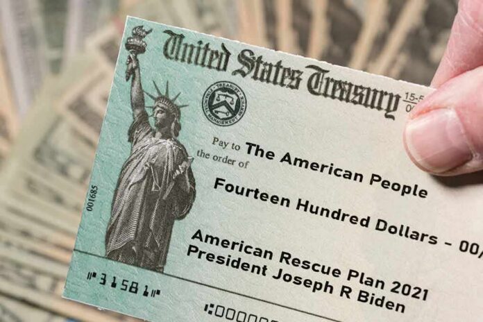 United States Treasury check held over a stack of cash
