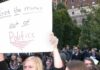 NYC Teacher Tied To Vigil Uproar Protesters holding a large handwritten sign at a crowded outdoor rally