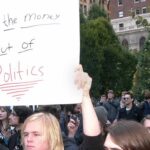 NYC Teacher Tied To Vigil Uproar Protesters holding a large handwritten sign at a crowded outdoor rally