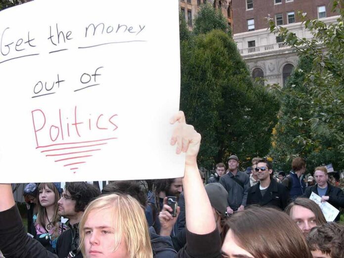 shutterstock_1982062058 Protesters holding a large handwritten sign at a crowded outdoor rally