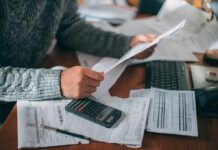 Election-Year Cash Hits Medicare Seniors Person reviewing bills with calculator at cluttered desk