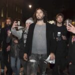 Prosecutors Paint Russell Brand as Serial Predator Russell Brand walking with a crowd at night