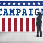 Proof-Of-Life Demands Rock Talarico Race Man in suit writing on large campaign banner with stars and stripes
